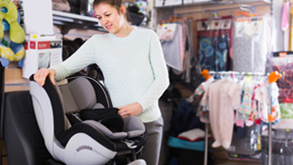 Mulher a escolher cadeira auto numa loja com vários artigos para crianças.